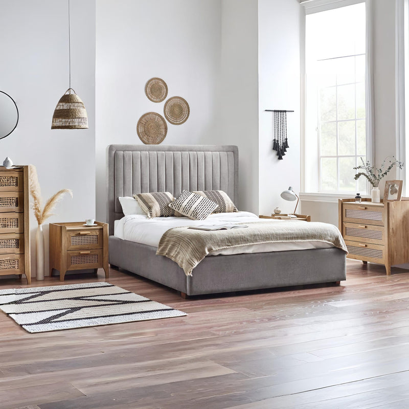 Modern bedroom with a gray upholstered bed, wooden nightstands, and decorative elements.
