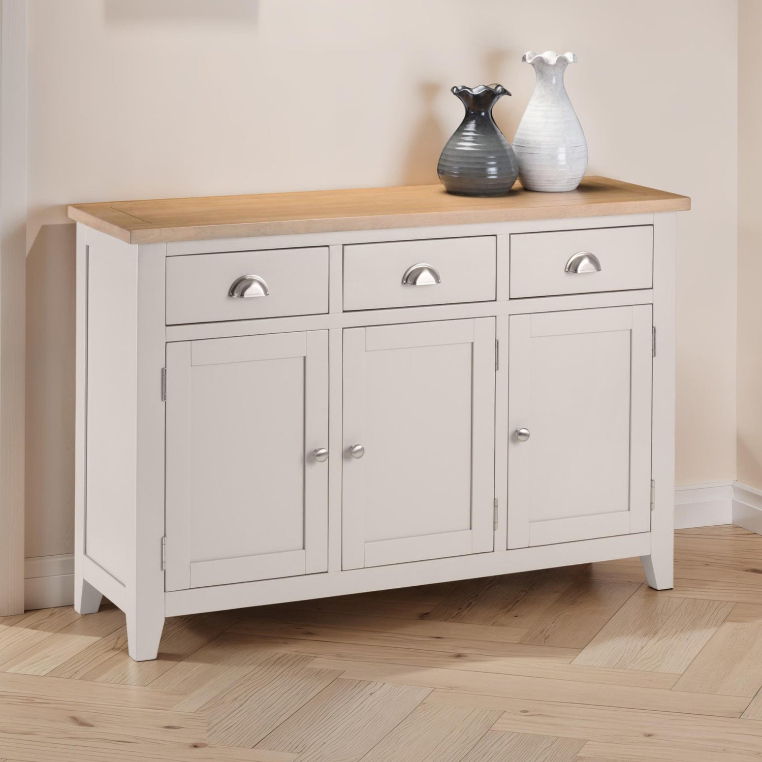 White sideboard with wooden top and three drawers in a room.