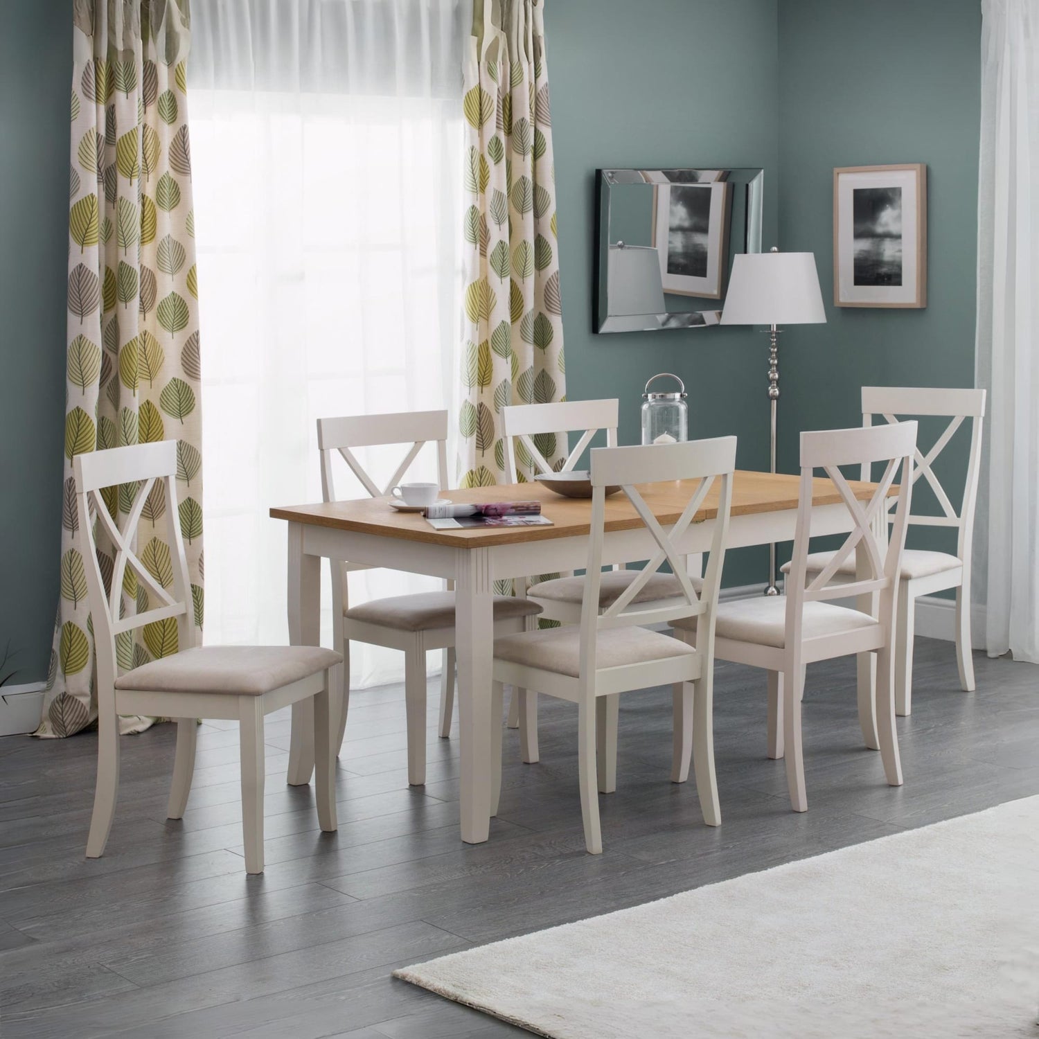 Dining room with a wooden table and white chairs against a green wall.