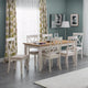 Dining room with a wooden table and white chairs against a green wall.