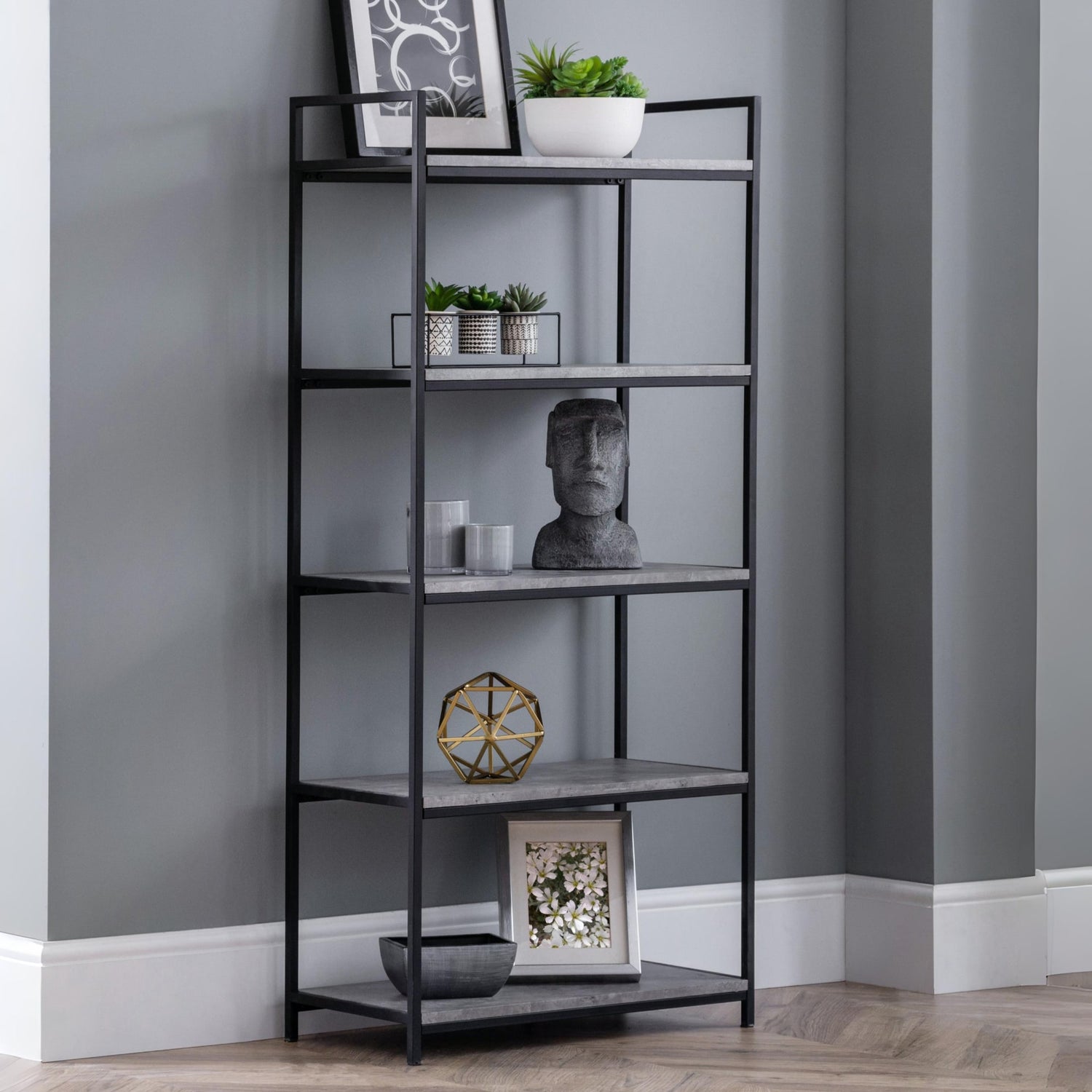 Black metal bookshelf with decorative items against a gray wall