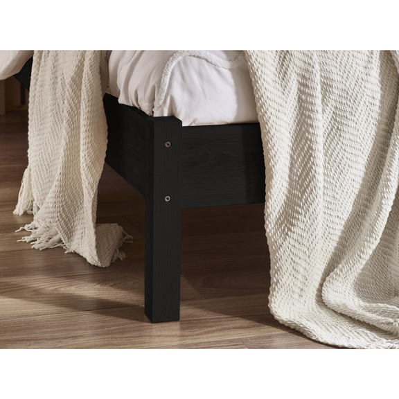 Black bed frame with white bedding and a textured white blanket on a wooden floor.