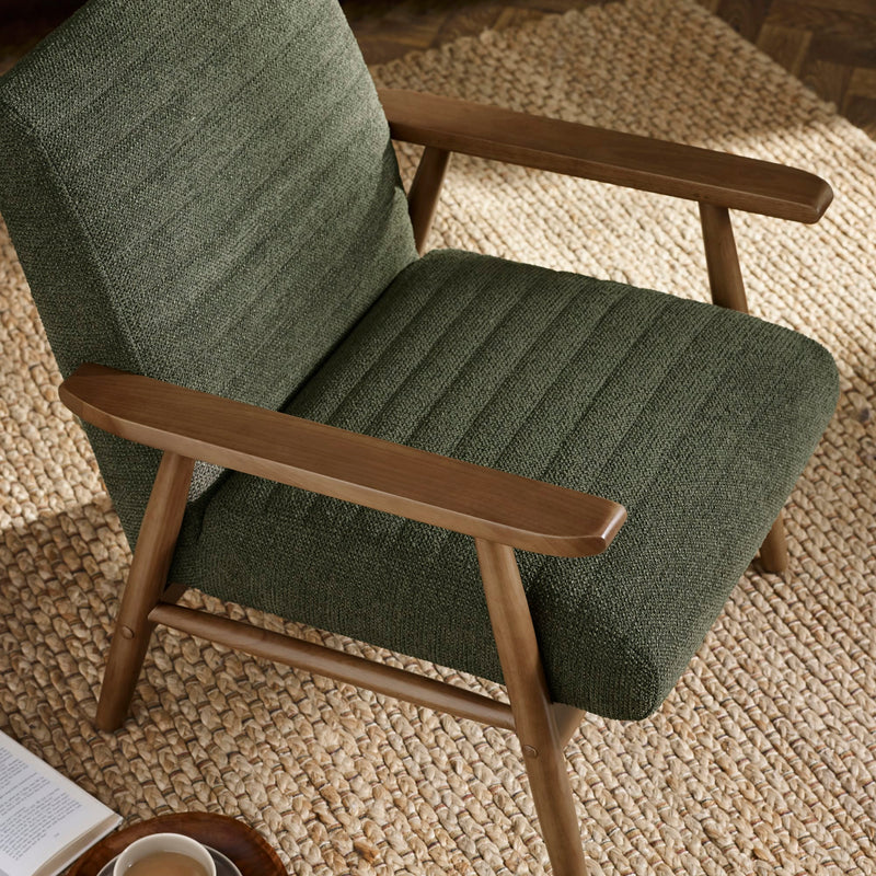 Green armchair with wooden arms and legs on a textured rug