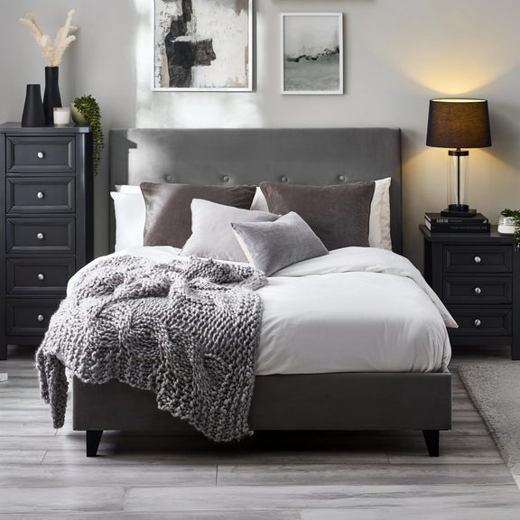 Modern bedroom with gray upholstered bed, nightstands, and wall art.