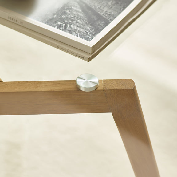Wooden table leg with a metal knob on a light background