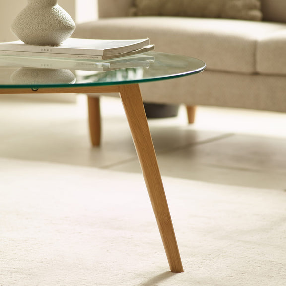 Glass coffee table with wooden legs in a living room setting