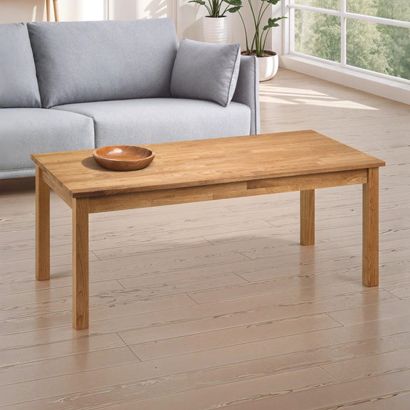 Wooden coffee table in a living room with a gray sofa and plants.