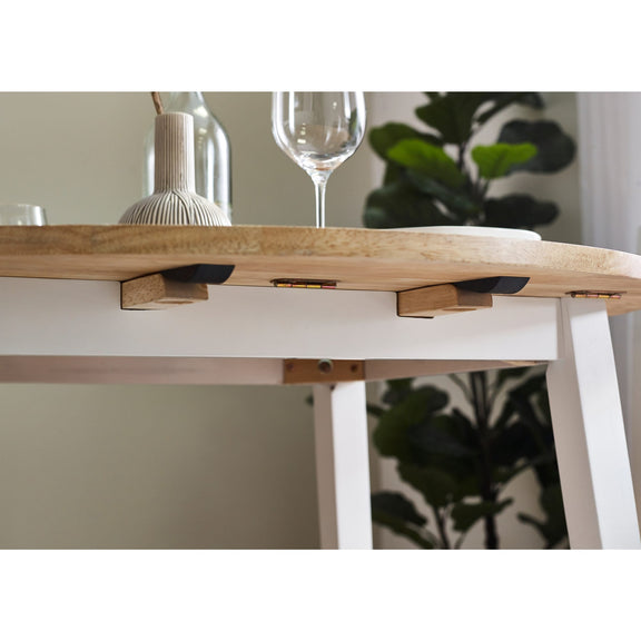 Wooden dining table with a white base, wine glasses, and decorative items.