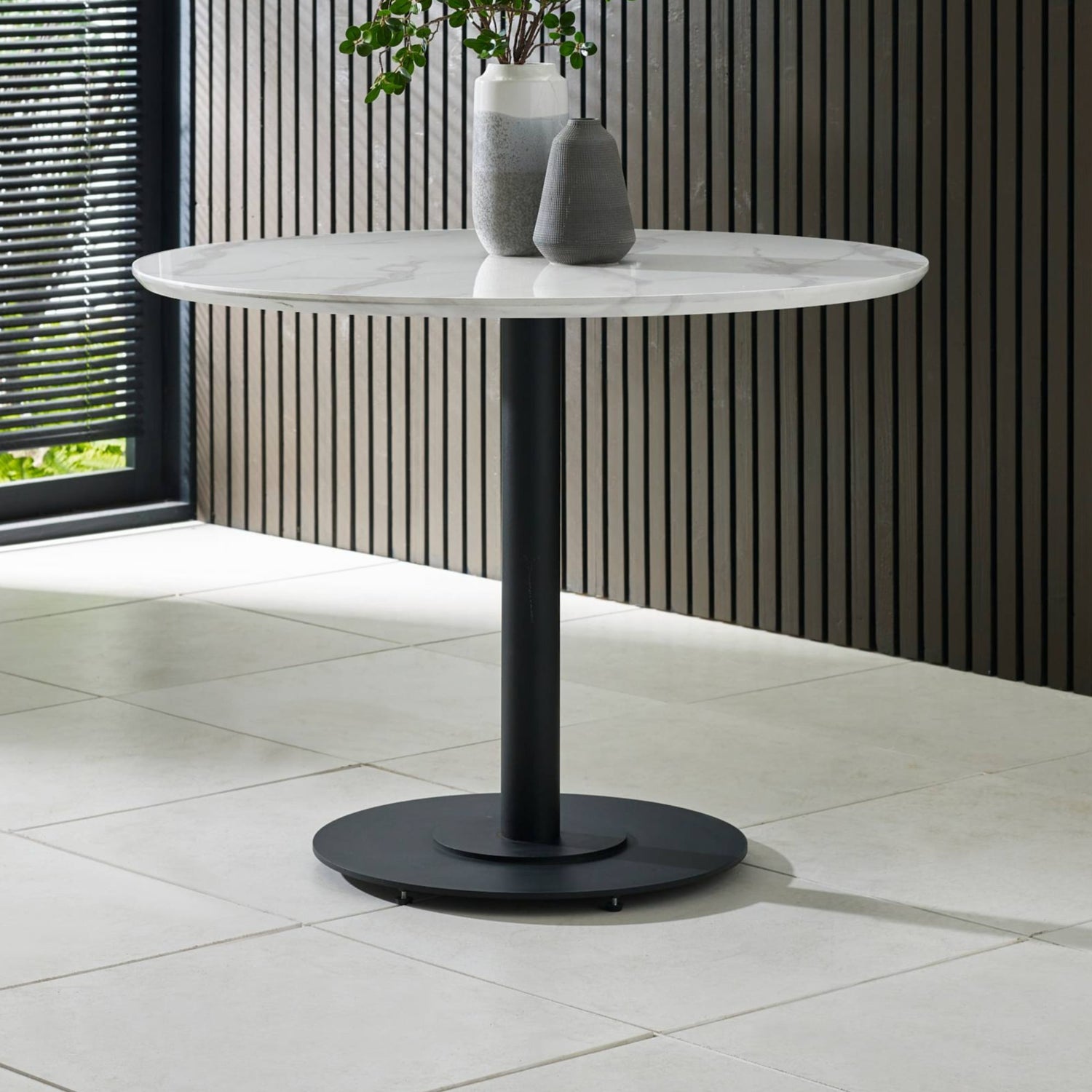 Round marble table with black base on a tiled floor