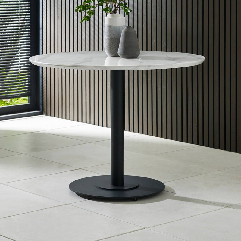 Round marble table with black base on a tiled floor