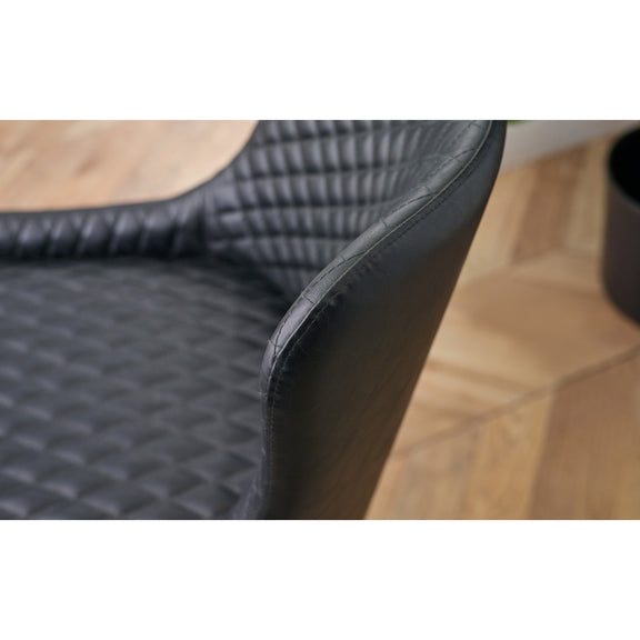 Close-up of a textured black car mat on a wooden floor.