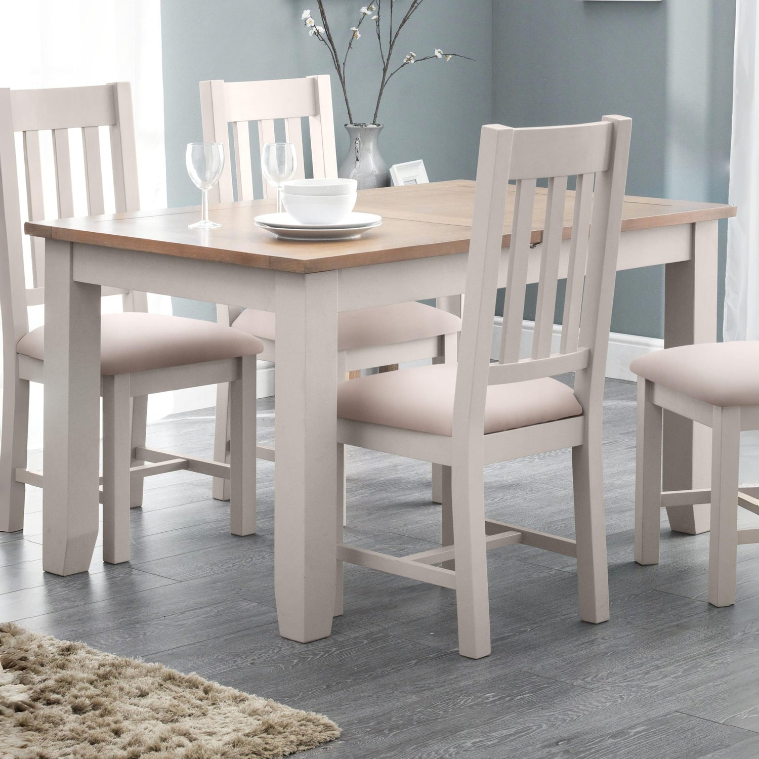 Dining table set with chairs in a room with a gray wall and wooden floor.