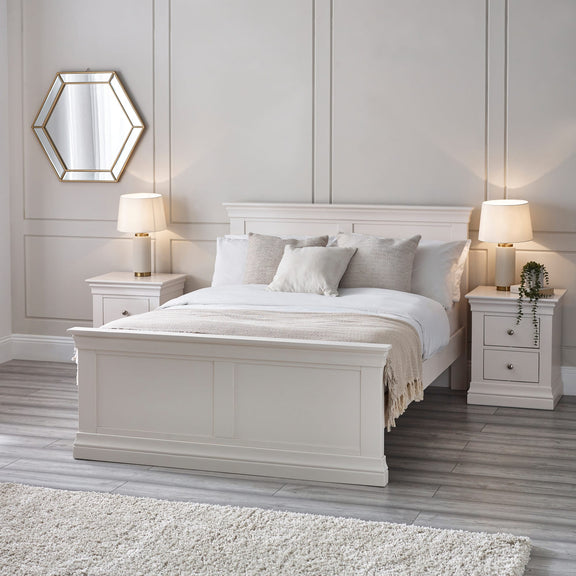 Neatly made bed with white bedding in a bedroom setting.