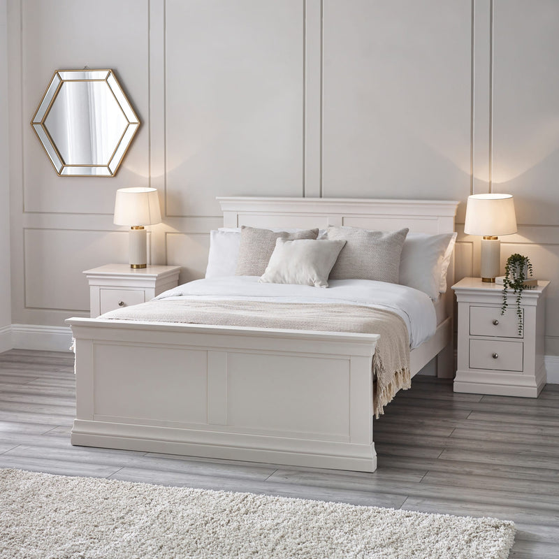 Neatly made bed with white bedding in a bedroom setting.