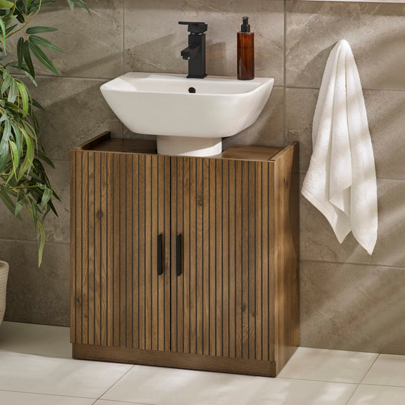 Bathroom setup with wooden cabinet, white sink, and towel on a tiled wall.