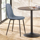 Blue chair next to a round black table on a wooden floor with a blurred background