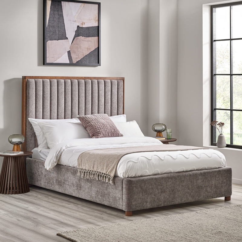 Gray upholstered bed with wooden headboard in a bedroom setting.