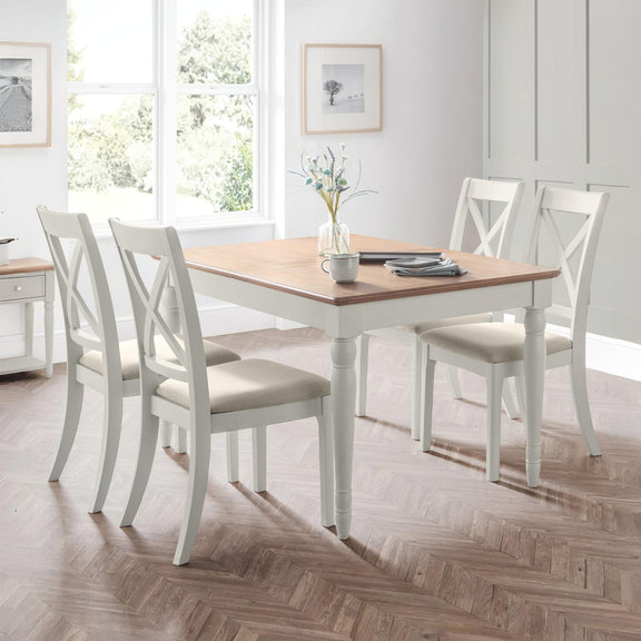 Dining room with a wooden table and white chairs on a wooden floor.