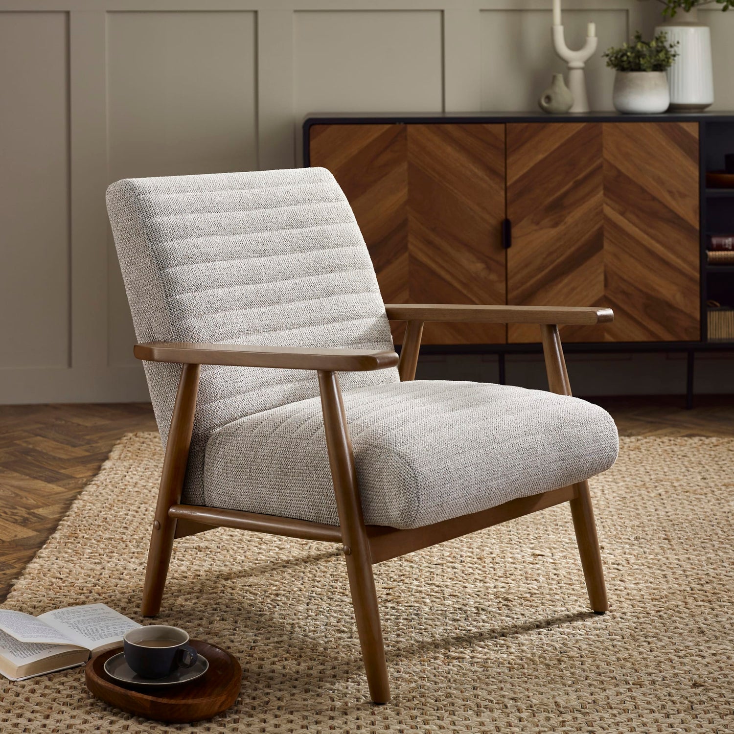 Gray upholstered armchair with wooden frame in a room setting.