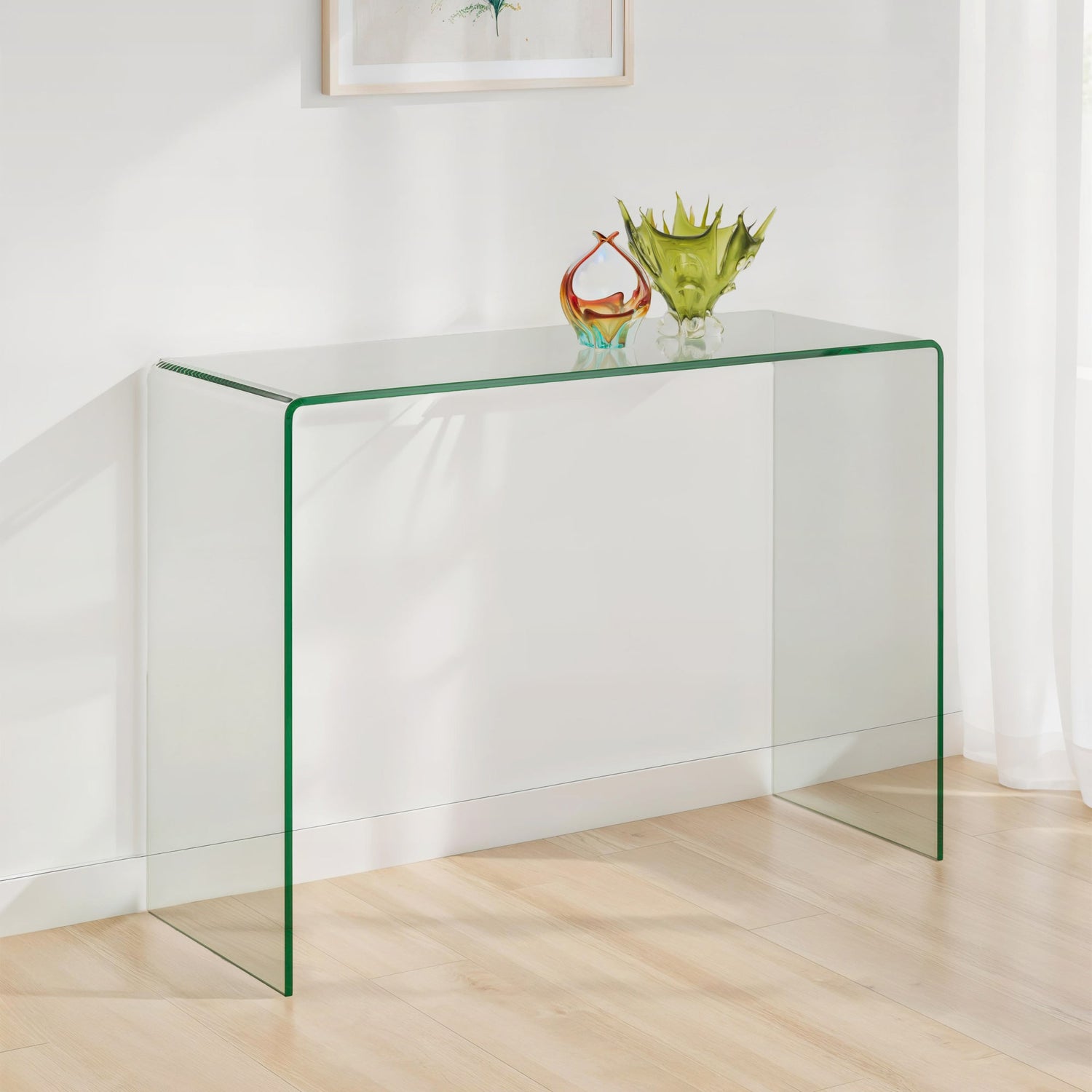 Clear glass console table with decorative items on a light wooden floor against a white wall.