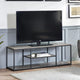 TV on a wooden stand in a living room setting with a white wall and framed pictures.