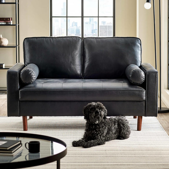 Black leather sofa in a living room with a dog sitting on the floor.