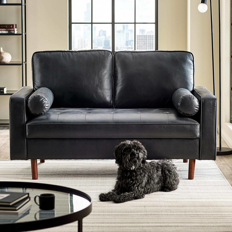 Black leather sofa in a living room with a dog sitting on the floor.