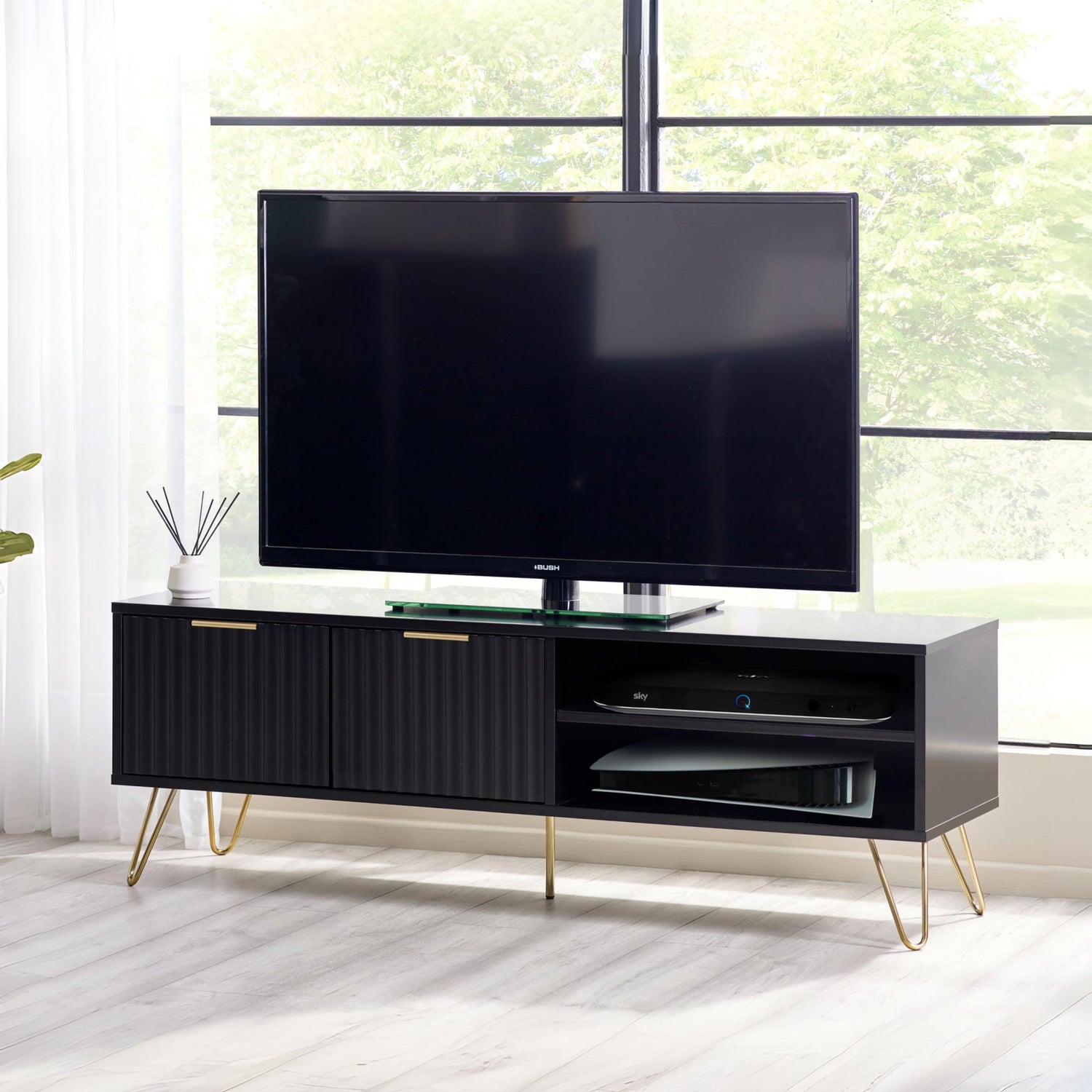 Black TV stand with a flat-screen TV in a room with large windows.