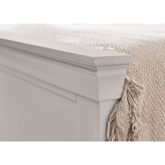 Gray wooden headboard with a beige blanket draped over the side