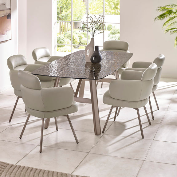 Dining room with a round glass table and eight chairs in a bright room.