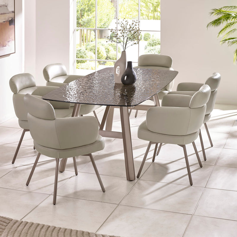 Dining room with a round glass table and eight chairs in a bright room.