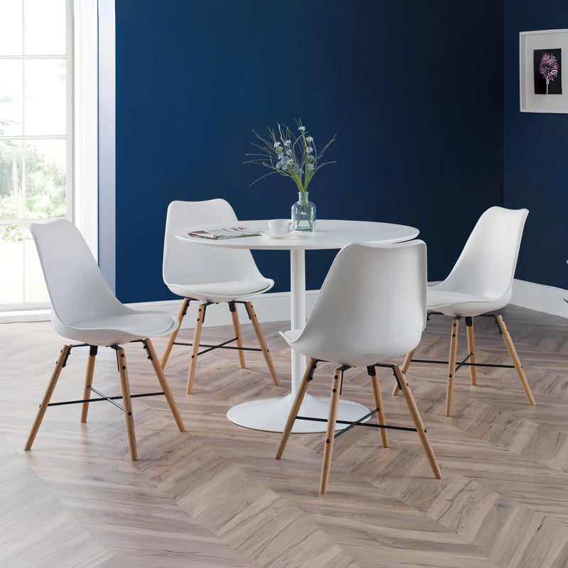 Dining area with white chairs and a round table against a blue wall.