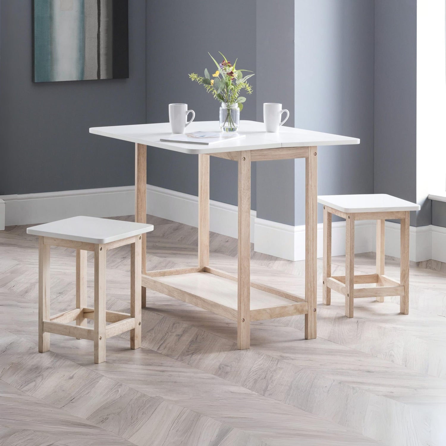 Dining table set with two stools in a room with gray walls and wooden flooring.