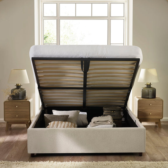 Beige upholstered bed with open storage compartment in a bedroom setting.