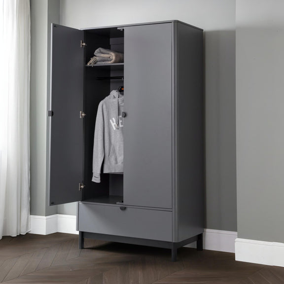 Gray wardrobe with open door showing clothes inside against a gray wall.