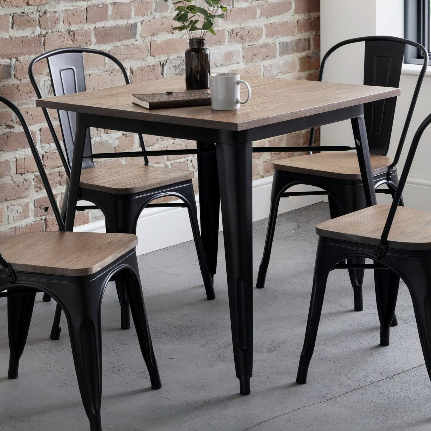 Dining table with chairs in a room with brick wall and window.