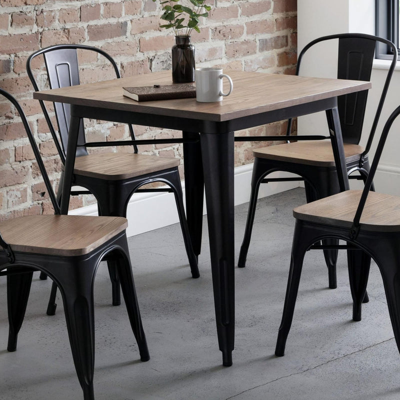 Dining table with chairs in a room with brick wall and window.