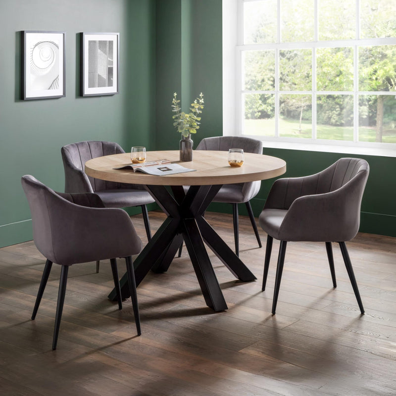 Round dining table with four gray chairs in a room with green walls and a window.