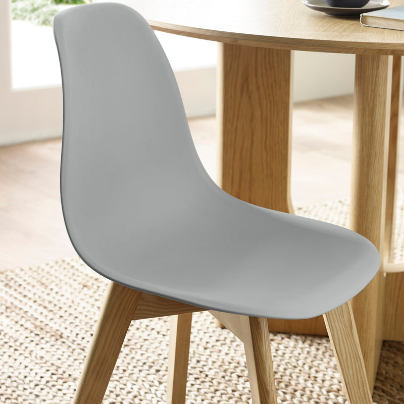 Gray chair with wooden legs in front of a wooden table.