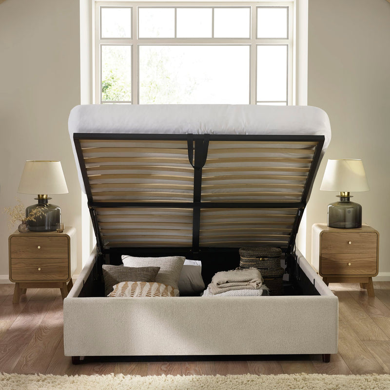 Beige upholstered bed with open storage compartment in a bedroom setting.