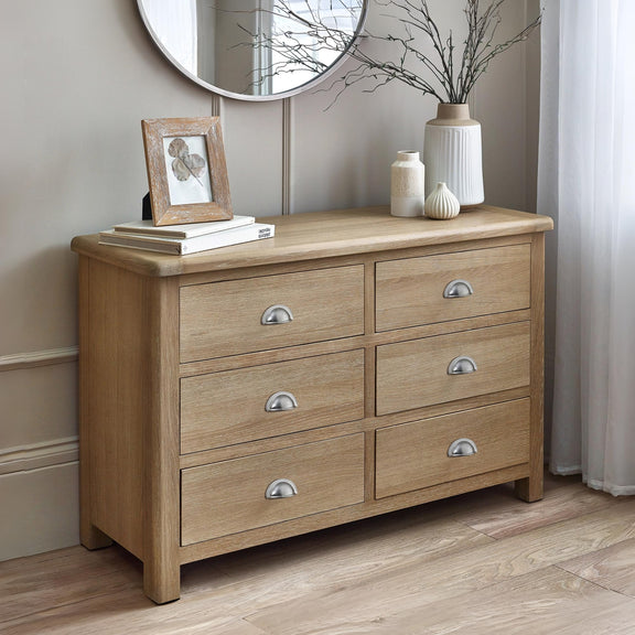 Wooden dresser with six drawers in a room setting.
