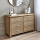 Wooden dresser with six drawers in a room setting.