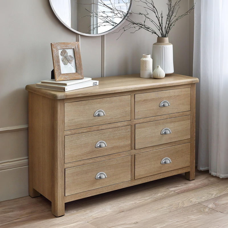 Wooden dresser with six drawers in a room setting.