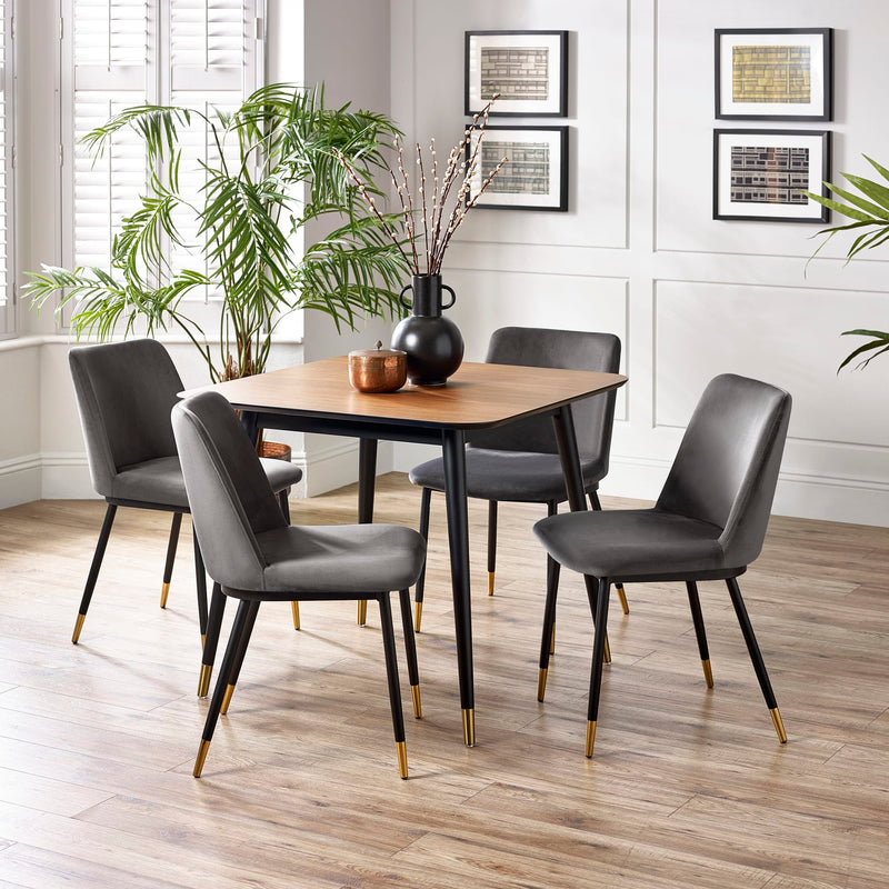 Dining room with a wooden table and gray chairs, plants, and framed pictures on the wall.