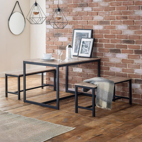Dining area with a table, chairs, and decor against a brick wall.
