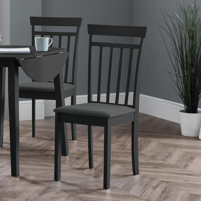 Dining room with black chairs and a table against a gray wall.
