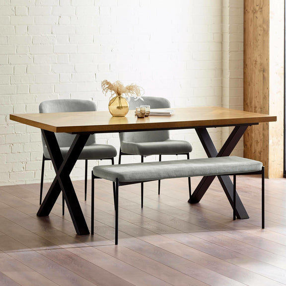 Dining table with chairs and a bench in a room with white brick walls.