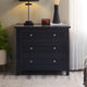 Black dresser with three drawers in a room setting with a lamp and plant.