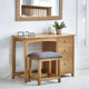 Wooden dressing table with mirror, stool, and decorative items in a bright room.