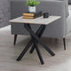 Small side table with black legs and a light wooden top, placed next to a gray sofa.